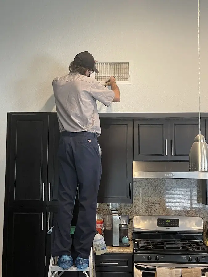 Technician inspecting an air vent during HVAC service in Pine Ridge